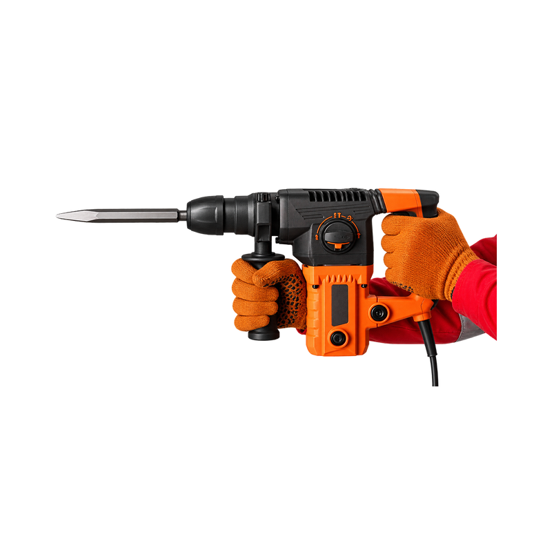 Orange-and-black corded chipping hammer held by gloved hands, with auxiliary grip, selector dial, and flat chisel pointing left.
